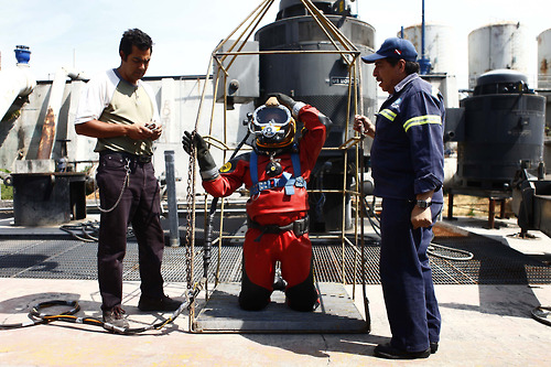 Mexican sewer diver Julio Cu Camara kneels in a cage while putting on his helmet before a dive at the city's drainage system plant in Mexico City